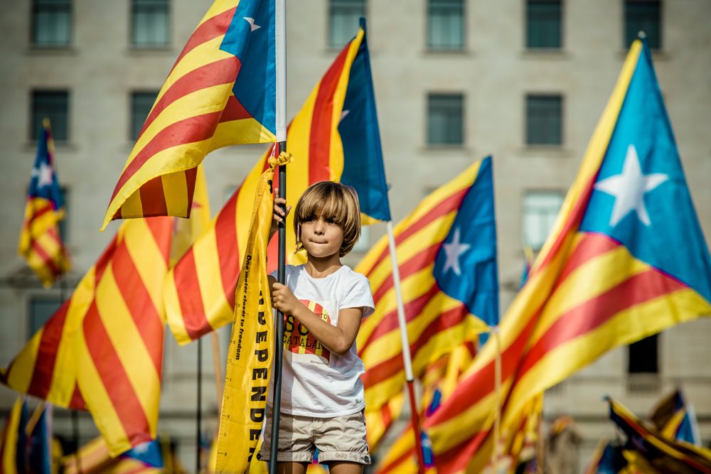 A young child waves the "Estelada" flag standing on the shoulders of her father during a pro-independence act organized by 'Omnium Cultural' and the 'ANC' at Barcelona's Catalonia Square