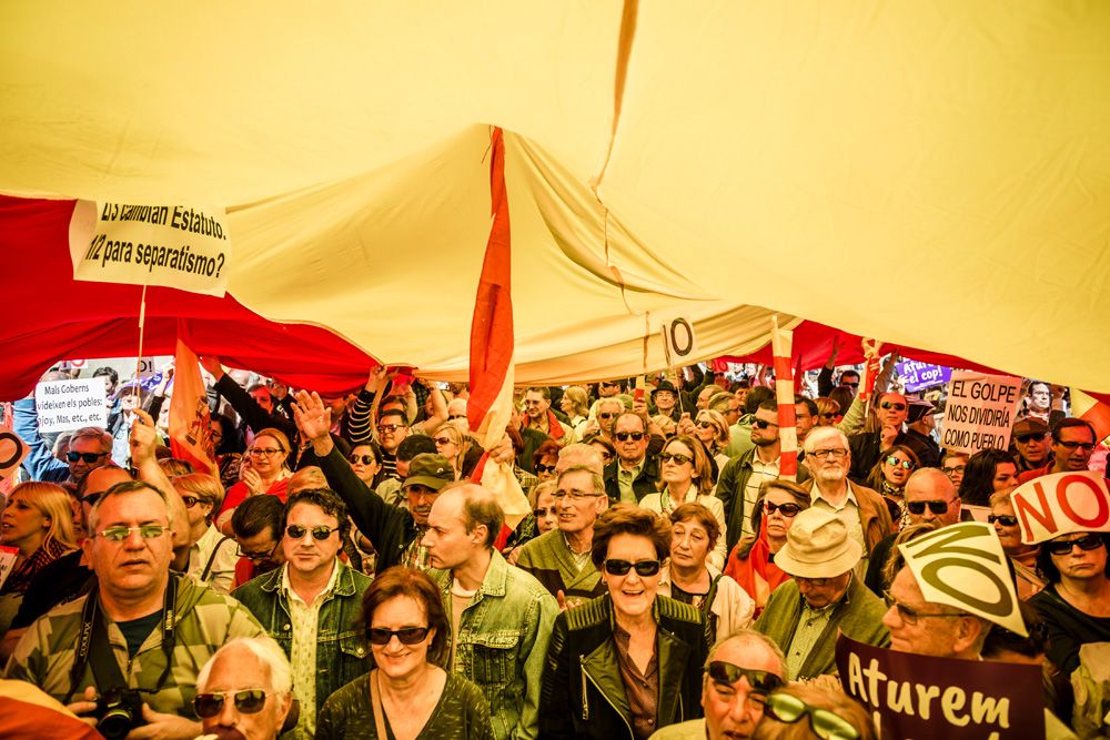 Anti-independence demonstrators with their placards shout slogans under a giant Spanish flag in front of the Generalitat in Barcelona against a hypothetical independence of Catalonia from Spain