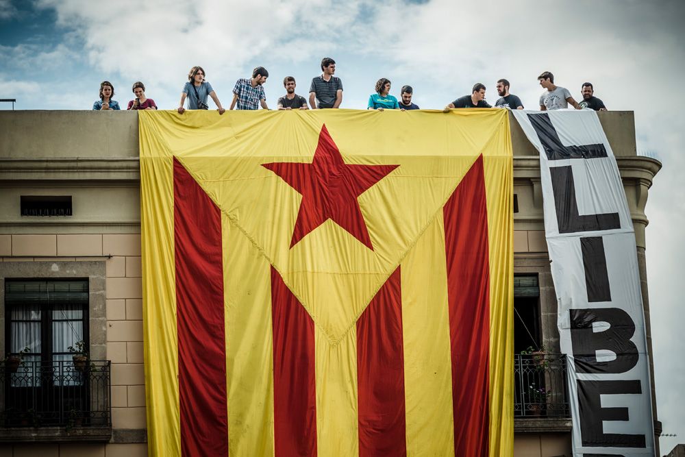 Barcelona, Spain. 24th September, 2016: Pro-independence supporters hang a giant 'estelada' flag on the facade of a building facing the St Jaume Place demanding 'freedom' during the local 'Castellers' day at the Merce 2016