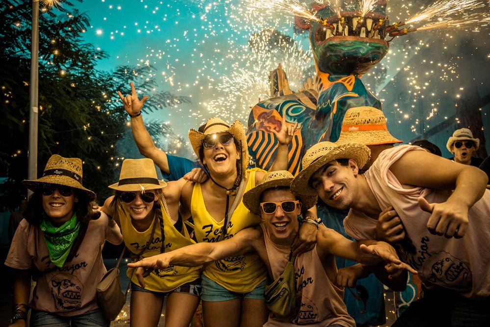 Sitges, Spain. August 23rd, 2013: A group of friends gather under the "Drac (dragon) de Sitges" for a photo as sets off his fireworks at the "Festa Major de Sitges".