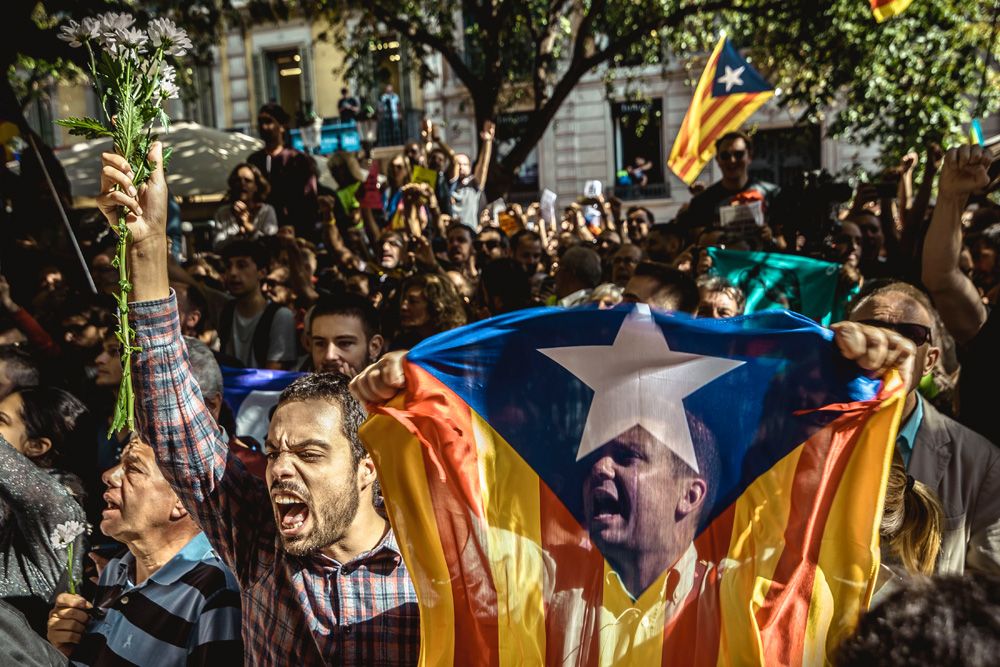 Barcelona, Spain. 20 September, 2017: Catalan separatists wave 'Estelada' flags and placards as they protest in front of the Catalan Economy Ministry as police officers search offices and arrests 12 senior officials in run-up to planned secession referendum at October1st. Spain's constitutional court has suspended the Catalan referendum law after the Central Government has challenged it in the CourtsCatalan separatists shout slogans as they protest in front of the Catalan Economy Ministry as police officers search offices and arrests 12 senior officials in run-up to planned secession referendum at October1st. Spain's constitutional court has suspended the Catalan referendum law after the Central Government has challenged it in the Courts
