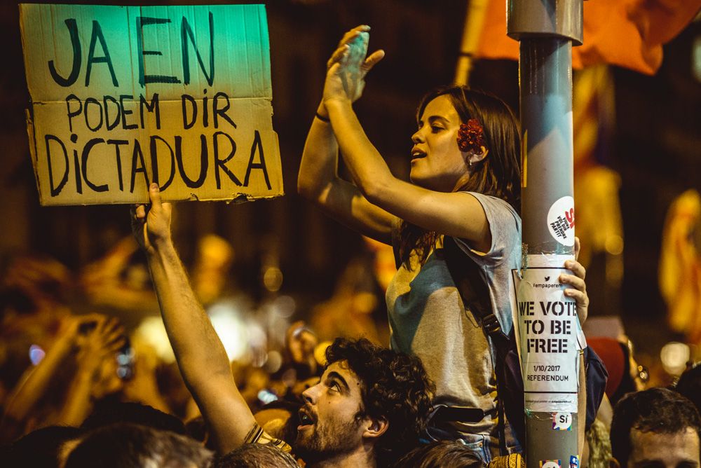 Barcelona, Spain. 20 September, 2017: Catalan separatists with their placard reading 'we can call it already dictatorship' protest in front of the Catalan Economy Ministry as police officers search offices and arrests 12 senior officials in run-up to planned secession referendum at October1st. Spain's constitutional court has suspended the Catalan referendum law after the Central Government has challenged it in the Courts