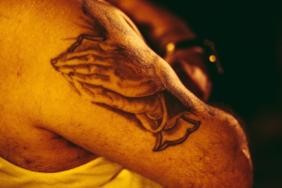 A tattoo of praying hands is seen on the arm of a   'costalero' (porter) of the 'Nuestra Senora de las Angustias' brotherhood during a break during the Good Friday procession through Barcelona