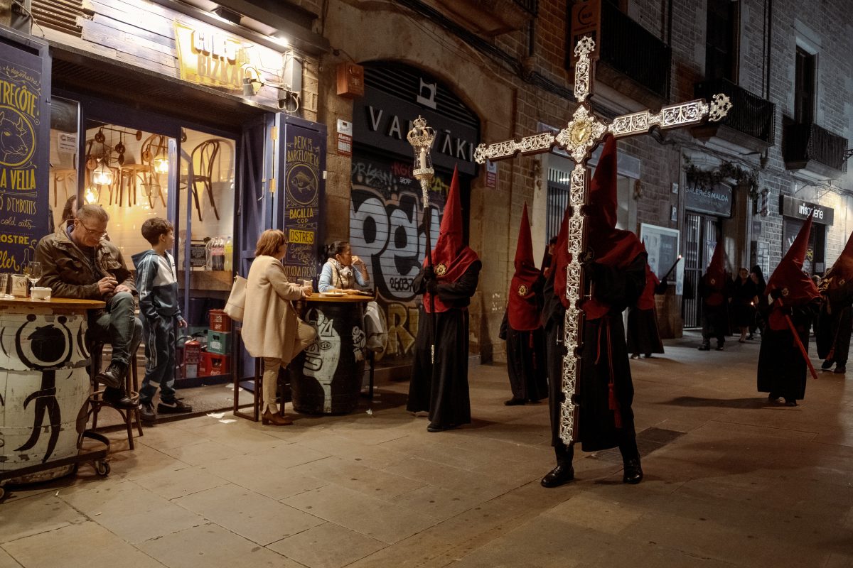 A hooded penitens of the 'Nuestra Senora de las Angustias' brotherhood carries a cross as he parades through Barcelona during the Good Friday procession