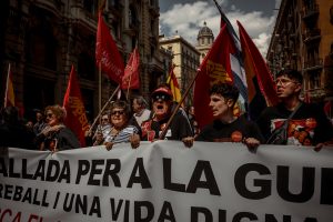 Protesters holding flags march at a Labour Day event organized by the major trade unions CC.OO and UGT to push for full employment.