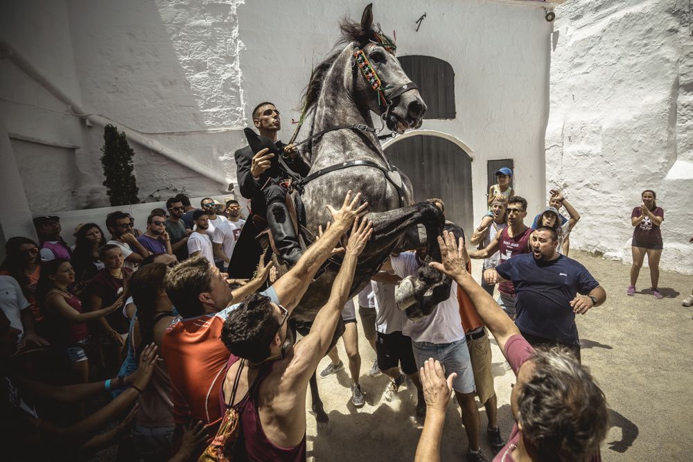 Ciutadella, Spain. 24 June, 2017: A 'caixer' (horse rider) rears up on his horse surrounded by a cheering crowd during the 'Caragol des Born' parade on the eve of the traditional 'Sant Joan' (Saint John) festival in Ciutadella de Menorca