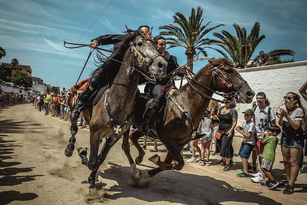 Two 'caixers' (horse riders) gallop together with their arms entwined during the training session for the 'Jocs des Pla' (medieval tournament) during the traditional 'Sant Joan' (Saint John) festival in Ciutadella de Menorca