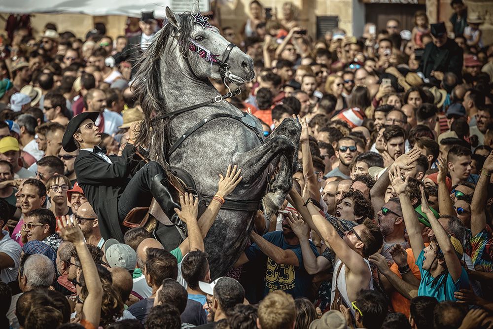 A 'caixer' (horse rider) rears up on his horse surrounded by a cheering crowd during the 'Caragol des Born' parade on the eve of the traditional 'Sant Joan' (Saint John) festival in Ciutadella de Menorca
