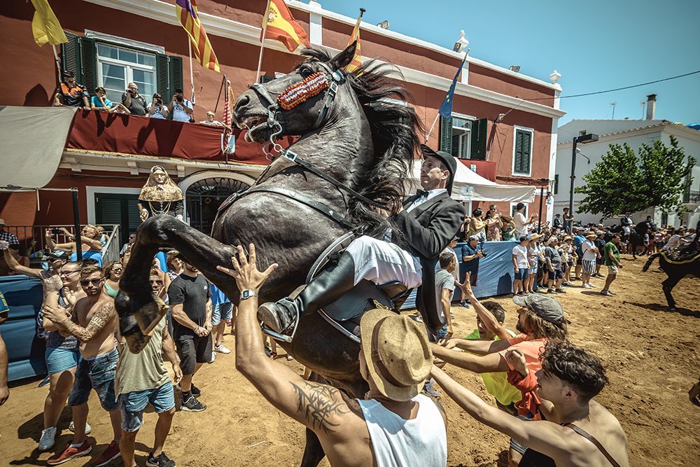 A 'caixer' (horse rider) rears up on his horse surrounded by a cheering crowd during the traditional 'Jaleo' at the Sant Jaume Festival in Es Castell