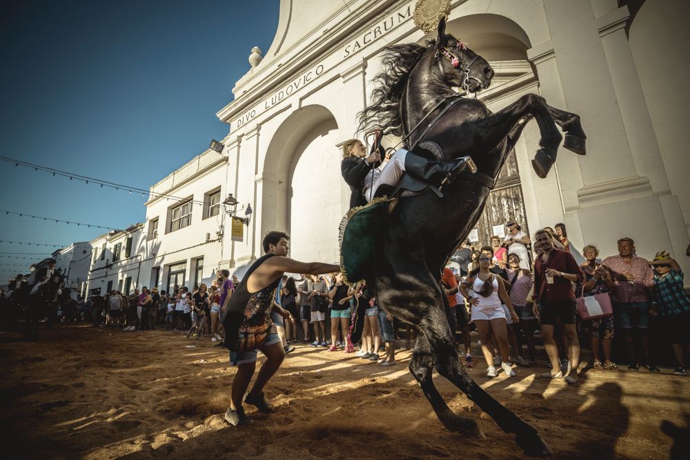 Sant Lluis, Spain. 27 August, 2016: 
A 'caixer' (horse rider) rears up on his horse in between the cheering crowd during the 'Jaleo' of the annual festival in Sant LLuis, the town's patron saint fiesta
