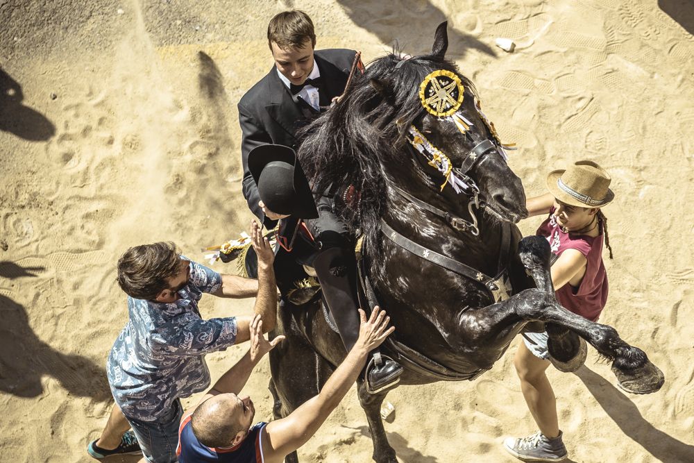 Ciutadella, Spain. 23 June, 2017: A 'caixer' (horse rider) rears up on his horse surrounded by a cheering crowd during the 'Caragol des Born' parade on the eve of the traditional 'Sant Joan' (Saint John) festival in Ciutadella de Menorca