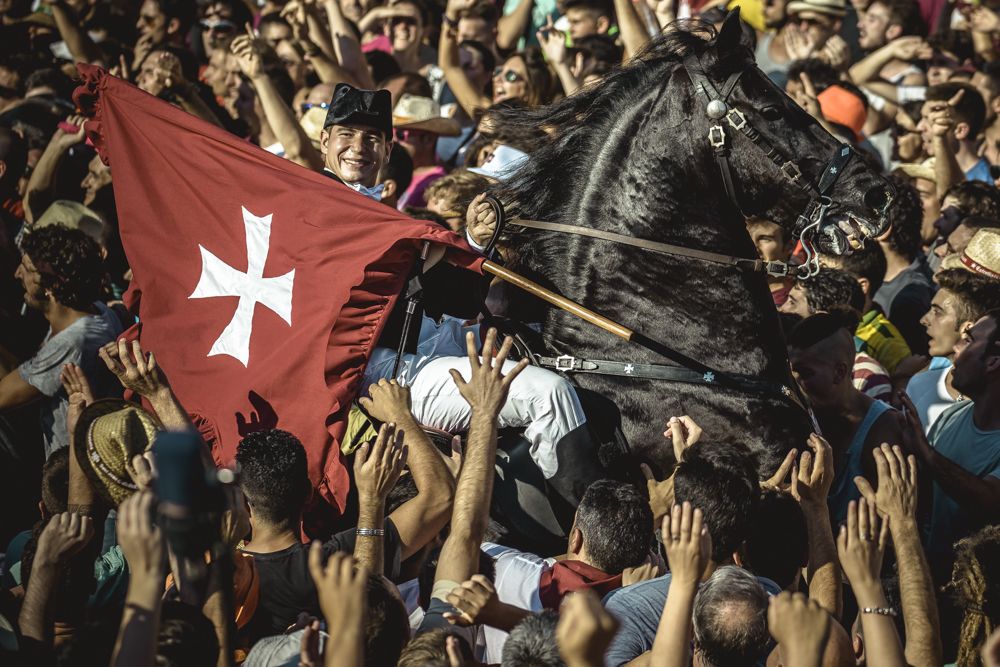 Ciutadella, Spain. 23 June, 2017: A 'caixer' (horse rider) rears up on his horse surrounded by a cheering crowd during the 'Caragol des Born' parade on the eve of the traditional 'Sant Joan' (Saint John) festival in Ciutadella de Menorca