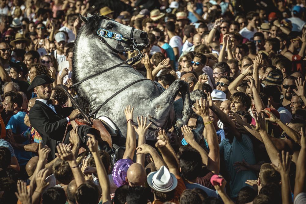 Ciutadella, Spain. 23 June, 2017: A 'caixer' (horse rider) rears up on his horse surrounded by a cheering crowd during the 'Caragol des Born' parade on the eve of the traditional 'Sant Joan' (Saint John) festival in Ciutadella de Menorca